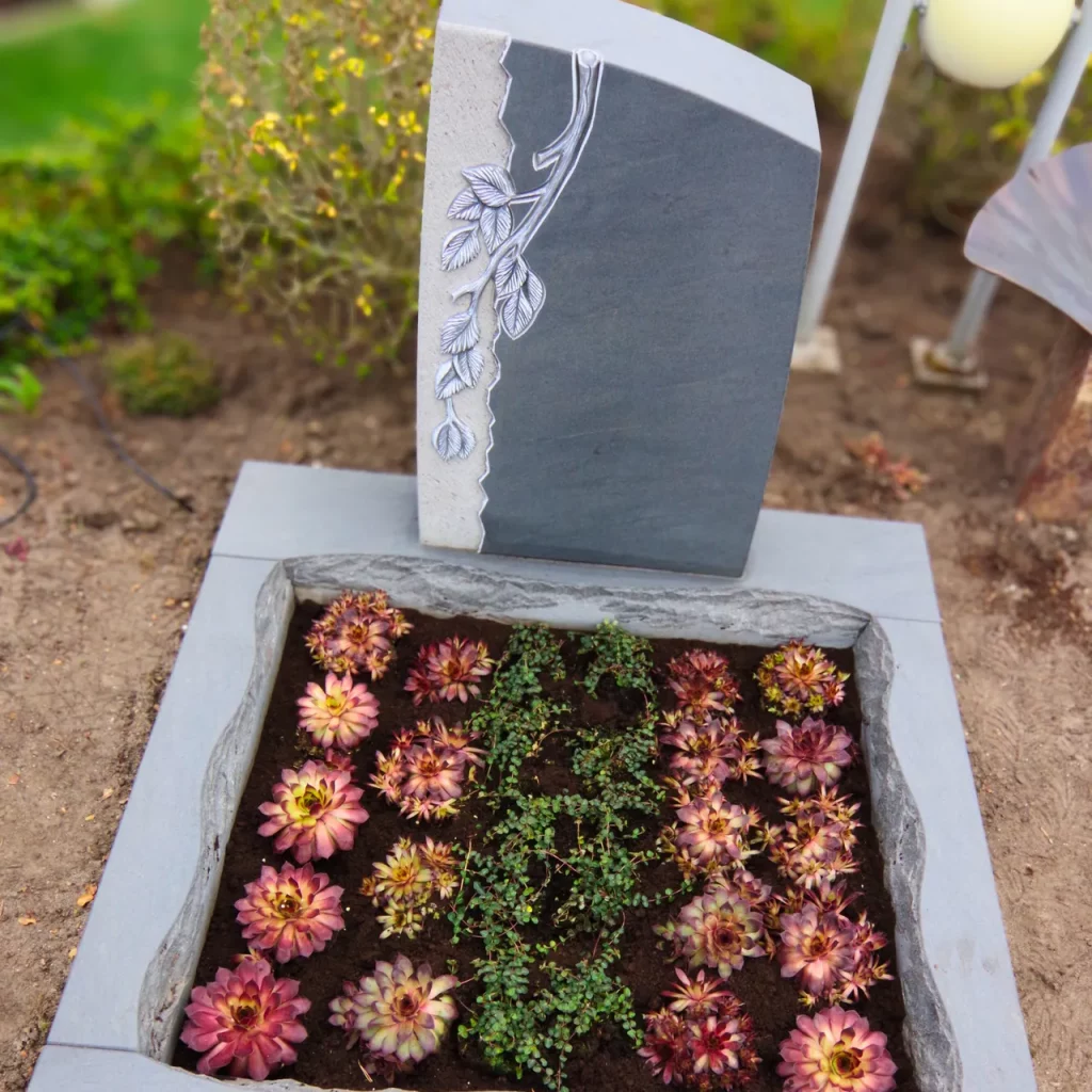 Urnengrabstein mit Einfassung und Bepflanzung